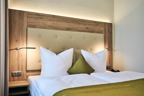 a bedroom with a bed with white sheets and green pillows at Lounge-Hotel Seeterrassen in Wandlitz