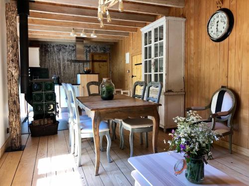 a dining room with a table and a clock on the wall at Gites à la ferme à 5 minutes du lac de Gerardmer. in Sapois