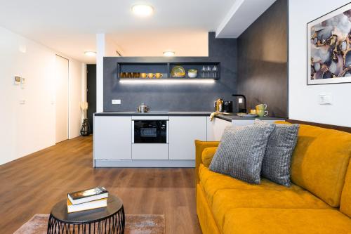 a living room with a yellow couch and a kitchen at Gerharts Premium City Living - center of Brixen with free parking and Brixencard in Bressanone