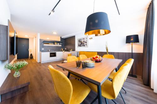 a dining room and living room with a table and yellow chairs at Gerharts Premium City Living - center of Brixen with free parking and Brixencard in Bressanone