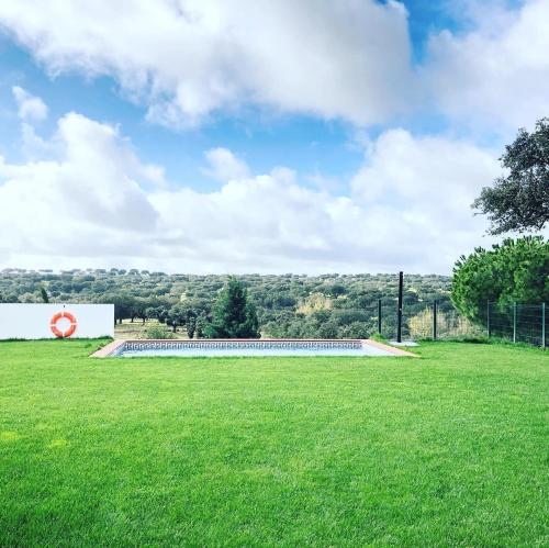 a large grassy field with a sign in the background at Casas da Faia - Nature Guest House in Arronches