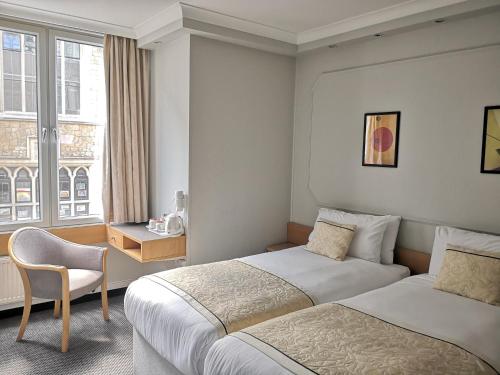 a hotel room with two beds and a chair at Lancaster Hall Hotel in London