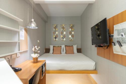 a small room with a bed and a television at Selah Pods Hotel Manila in Manila