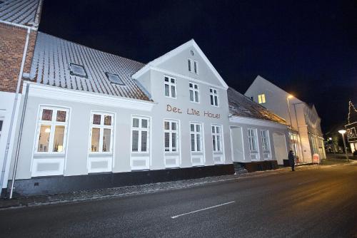ein weißes Gebäude am Straßenrand in der Nacht in der Unterkunft Det Lille Hotel in Rønne