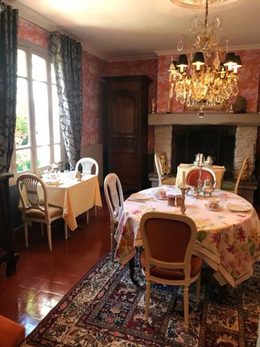 une salle à manger avec deux tables et un lustre dans l'établissement Manoir des Lions de Tourgéville, à Deauville