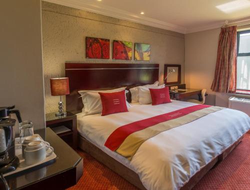 a hotel room with a large bed with red pillows at Peermont Metcourt Inn at the Grand Palm, Gaborone in Gaborone