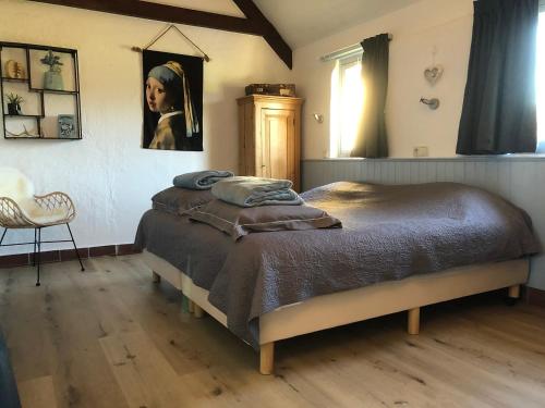 een slaapkamer met een bed met een schilderij van een vrouw bij De Heidehoeve in Wezep