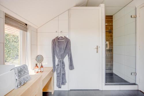 a bathroom with a shower and a robe hanging on a wall at De Heidehoeve in Wezep