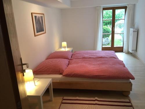a bedroom with a bed with red sheets and a window at Ferienwohnung Watzmann - Haus Martin in Bischofswiesen