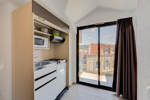- une cuisine avec vue sur un balcon dans l'établissement Residhotel Les Coralynes, à Cannes
