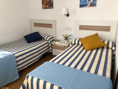 zwei Betten in einem Zimmer mit blau-weißen Streifen in der Unterkunft HOTEL CARAVIA in Caravia