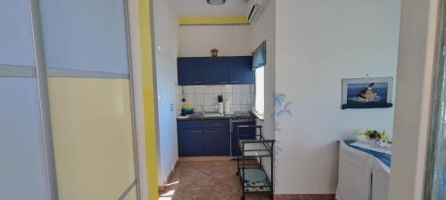 a small kitchen with blue cabinets and a sink at Apartments Villa Krasa in Lovran