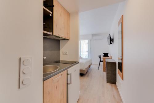 a kitchen with wooden cabinets and a sink at Residhotel Les Coralynes in Cannes