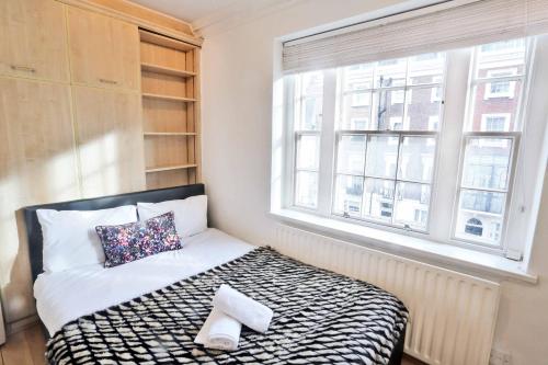 - une petite chambre avec un lit et une fenêtre dans l'établissement L'ambassadeur 5 room Belgravia Embassies TownHouse, à Londres