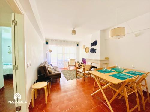a dining room and living room with a table and chairs at Água à Vista - Apto com 2 quartos e Piscina in Ericeira