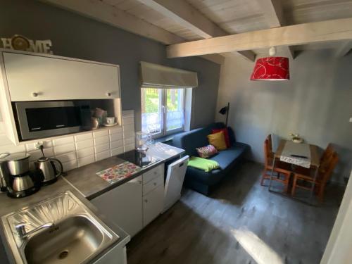 Domek na Leśnej في بوغورزيلكا: مطبخ وغرفة معيشة مع أريكة زرقاء وطاولة