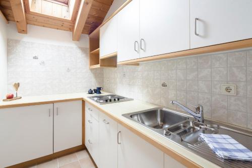 a kitchen with white cabinets and a sink at Am Rainell Hof in Ortisei