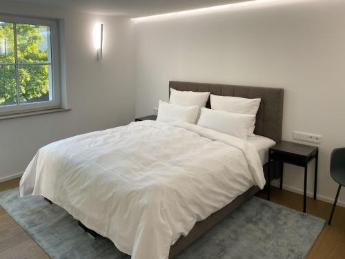 Toploft Serviced Apartments في كرايلسهايم: غرفة نوم بسرير كبير عليها شراشف ووسائد بيضاء