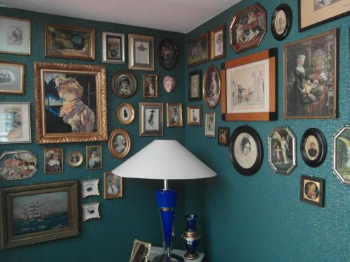 a room with a wall full of pictures and a lamp at Pension Antik in Bad Lobenstein
