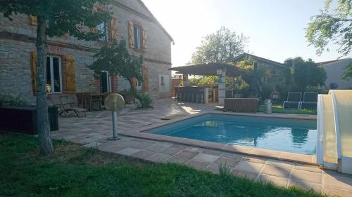 uma piscina num quintal ao lado de um edifício em La Ferme aux portes de Montauban - Avec piscine em Albias