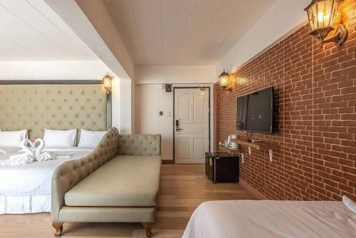 a hotel room with a bed and a couch and a tv at SUDYOD HOTEL in Ban Bang Bamru