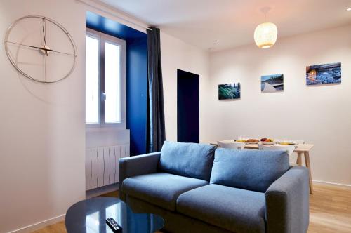 a living room with a blue couch and a table at NuitéeJour Niort Centre in Niort