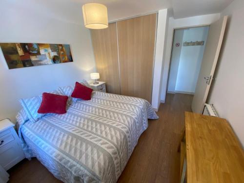 1 dormitorio con 1 cama con 2 almohadas rojas en Apartamento Casco Histórico en San Carlos de Bariloche