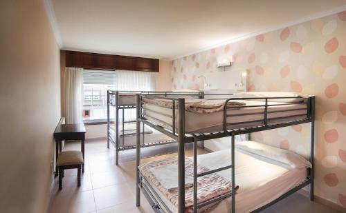 a room with three bunk beds and a desk at Albergue O Cruceiro in Caldas de Reis