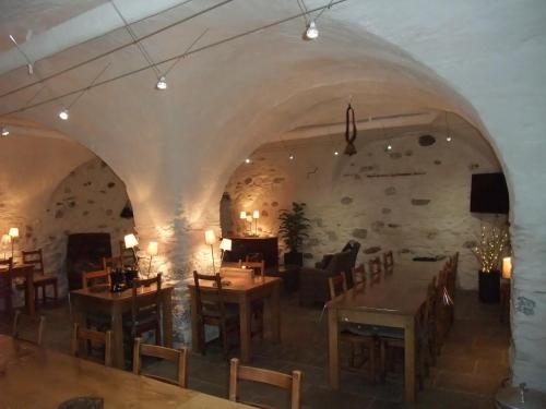 une salle à manger avec des tables et des chaises et un mur en pierre dans l'établissement Domaine du Grand Cellier - Insolite en Savoie, à Tournon