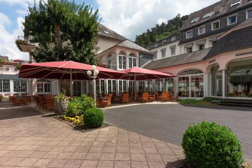 un patio con tavoli e ombrelloni di fronte a un edificio di Häcker's Fürstenhof a Bad Bertrich