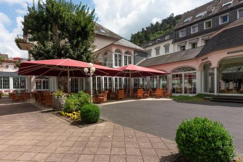 a patio with tables and umbrellas in front of a building at Häcker's Fürstenhof in Bad Bertrich