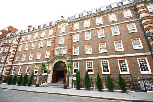 a large red brick building with trees in front of it at Gem Fitzrovia Hotel in London