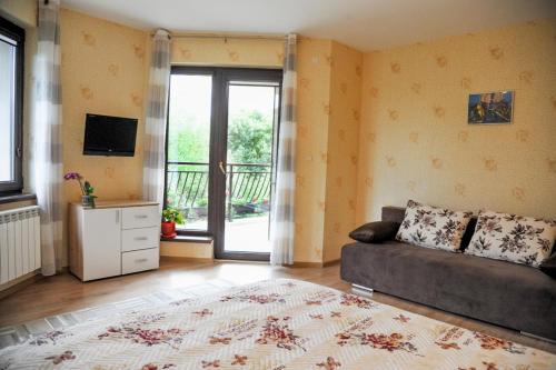 a living room with a couch and a sliding glass door at Къща за гости АКАЦИЯ in Ravna Gora