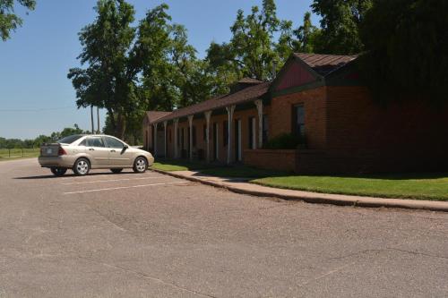 a car parked in a parking lot next to a building at The Evergreen Motel in Kansas in Pratt
