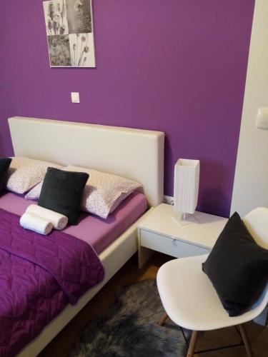 a purple bedroom with a bed and a chair at Tomena apartments in Trogir