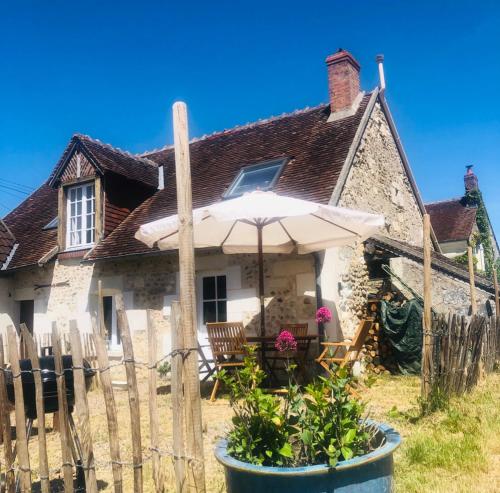 an old stone cottage with an umbrella and a chair at Côte du Jardin in Pouillé