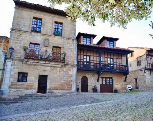 een oud stenen gebouw met balkons in een straat bij Akla Suites con Jacuzzi Santillana in Santillana del Mar