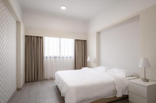 a white bedroom with a large bed and a window at salmiya - Amman -Family only in Kuwait