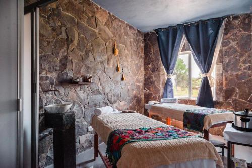 Cette chambre comprend 3 lits et un mur en pierre. dans l'établissement Lila Hotel, à Atotonilco