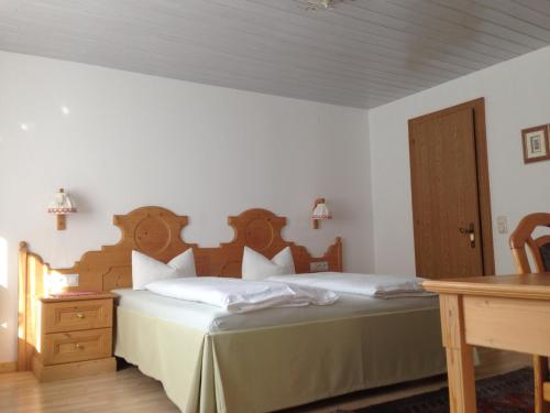 a bedroom with a bed with a wooden headboard and a table at Landhaus Fuchsenstube in Schruns-Tschagguns
