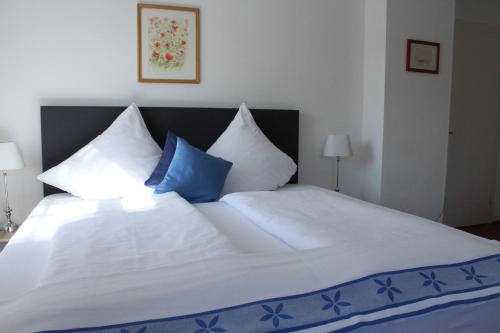 a large white bed with blue and white pillows at Galerie Riesling in Trittenheim