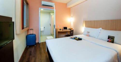 a hotel room with a large bed and a desk at ibis Ourinhos in Ourinhos