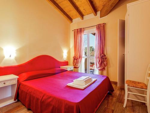 ポルペナッツェ・デル・ガルダにあるCozy Holiday Home in Lombardy with Swimming Poolの赤いベッド1台(赤い毛布付)が備わるベッドルーム1室が備わります。