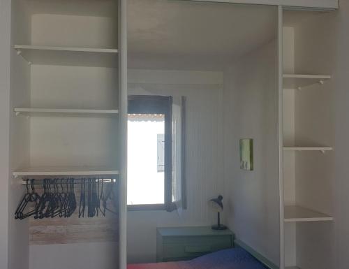Cette chambre dispose d'étagères blanches et d'une fenêtre. dans l'établissement Les vagues bleues, à La Ciotat