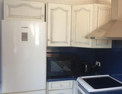 une cuisine avec des armoires blanches et un réfrigérateur blanc dans l'établissement Les vagues bleues, à La Ciotat
