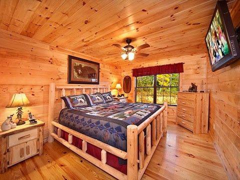 1 dormitorio con 1 cama grande en una cabaña de madera en Caught Ya Peek'n en Sevierville