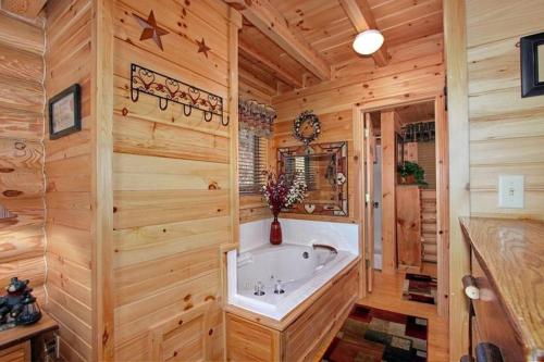 ein Bad mit einer Badewanne in einem Zimmer mit Holzwänden in der Unterkunft Kiss Me Goodnight in Sevierville