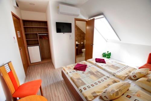 een slaapkamer met een bed en een kamer met een tv bij Fehér Hajó Panzió és Vendéglő in Győr