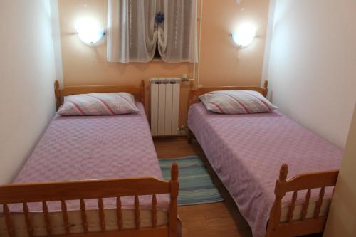 two beds in a small room with pink sheets at Haus Milan AP 1 in Fažana