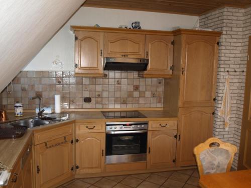 a kitchen with wooden cabinets and a sink at Ferienwohnung Wiesengrund in Hahnstätten
